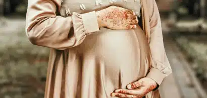 Femme enceinte en robe beige avec henné sur les mains.