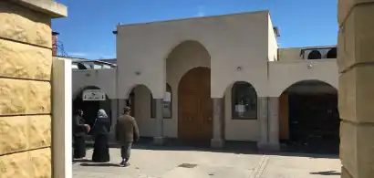 Entrée de mosquée avec personnes marchant devant.