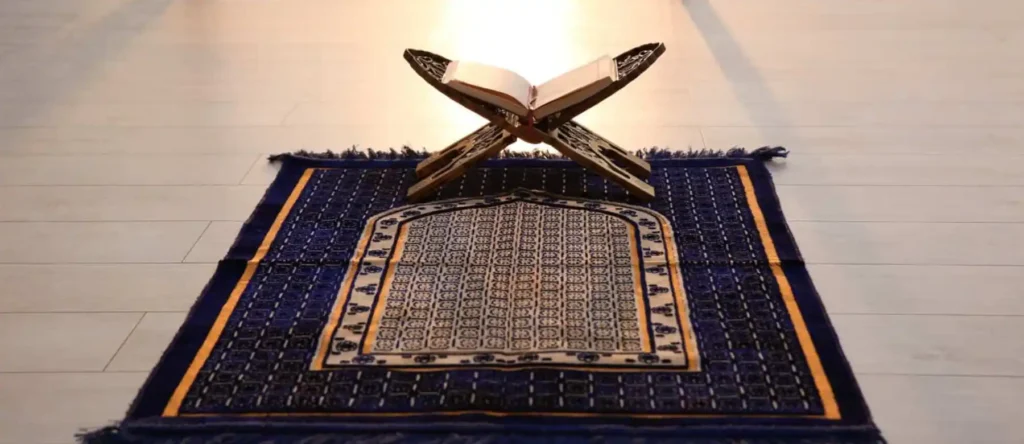 Coran ouvert sur un tapis de prière bleu.