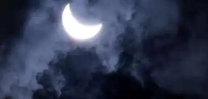 Lune croissante éclairée à travers des nuages nocturnes.